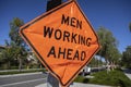 Orange diamond shaped traffic control sign reading Ã¢â¬ÅMen Working AheadÃ¢â¬Â